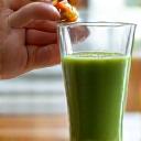 Woman adding a supplement to a smoothie, symbolizing daily routine integration.